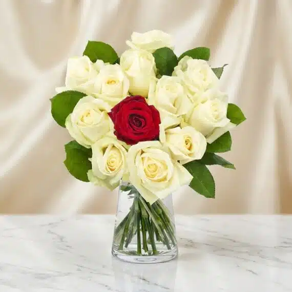 Arreglo Floral CARLA: Diseño Premium con 12 Rosas de Tallo Largo Arreglo floral CARLA con 12 rosas de tallo largo, una roja central y once blancas, en un jarrón de cristal sobre mármol.