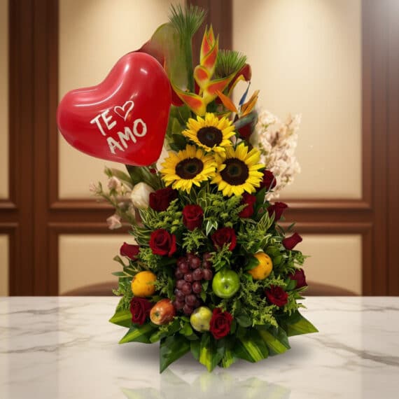 Arreglo floral premium con girasoles, rosas rojas, frutas tropicales (uvas, manzanas, naranjas) y un globo rojo de corazón co