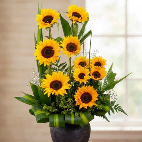 Arreglo floral GIULIANA con girasoles radiantes en un jarrón oscuro, ideal para ecommerce de floristería, con fondo elegante