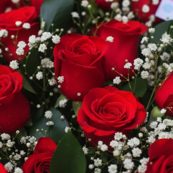 Primer plano extremo de un arreglo floral 'Quiero Amarte' con rosas rojas vibrantes, gotas de rocío sutiles y follaje verde,