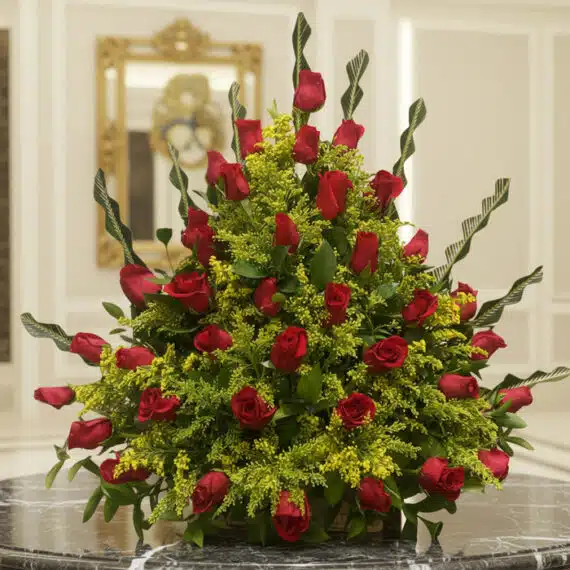 Arreglo floral premium con rosas rojas Cupido y follaje verde, sobre una mesa de mármol en un lobby de hotel boutique, ideal