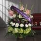 Arreglo floral fúnebre 'Te Fuiste' con lirios blancos, gladiolos rosados y hortensias verdes, adornado con una cinta morada d