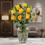 Jarrón de cristal con doce rosas amarillas vibrantes y follaje verde, sobre una superficie de mármol en un entorno de lujo.